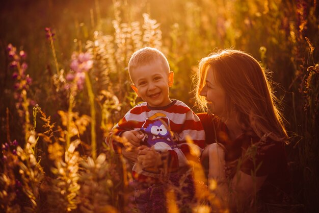 Mama siedzi z synem na polu w światłach wieczornego słońca