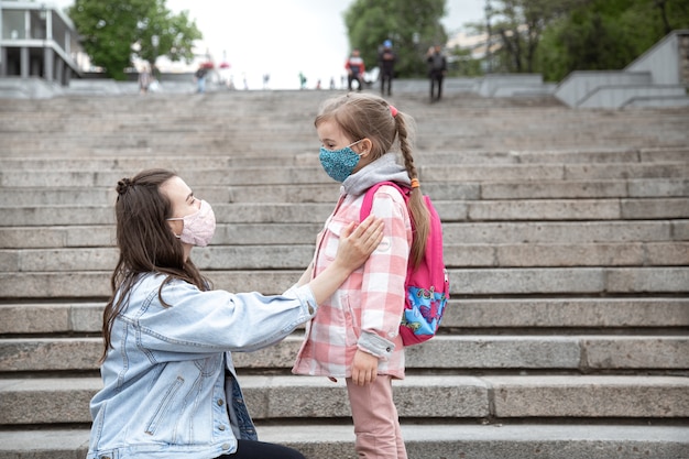 Mama z córeczką, uczennicą, na schodach w drodze do szkoły. Koncepcja edukacji w zakresie pandemii koronawirusa.