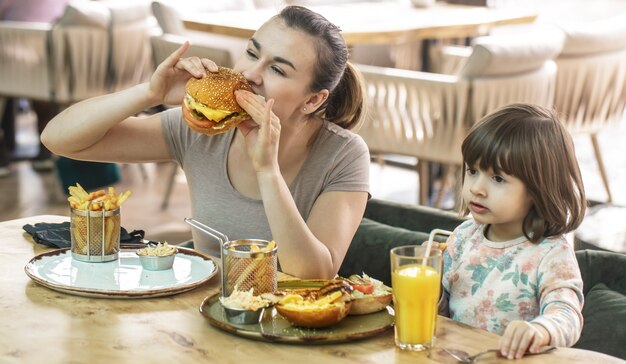 Mama z uroczą córką, jedzenie fast food w kawiarni