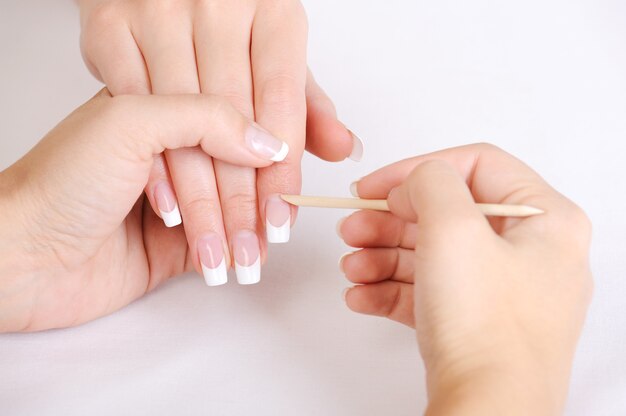 Manikiurzystka robi czyszczenie skórek na kobiecych palcach