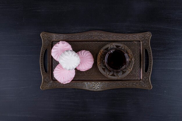 Marshmallows ze szklanką herbaty w metalowym talerzu, widok z góry