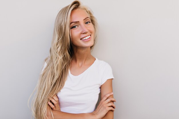 Marzycielska opalona kobieta z uśmiechem. modelka o blond włosach, śmiejąc się do kamery.