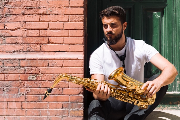 Bezpłatne zdjęcie marzycielski muzyk pozuje z saksofonem