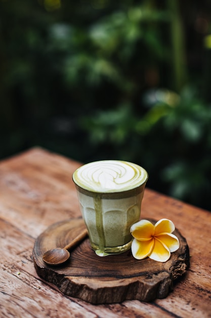 Matcha latte w przezroczystym szkle z kwiatkiem