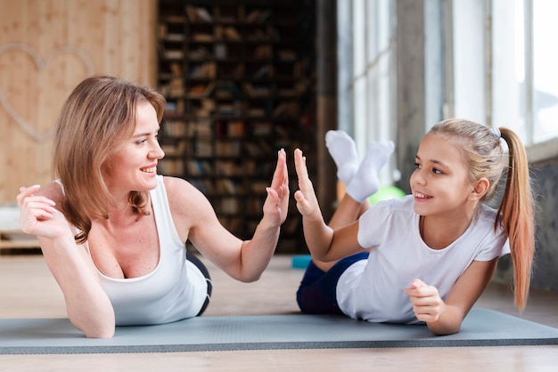 Matka i córka wysoko fiving na matach do jogi