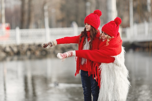 Matka i dziecko w czapki zimowe z dzianiny na rodzinne wakacje świąteczne. Ręcznie robiona wełniana czapka i szalik dla mamy i dziecka. Dziewiarskie dla dzieci. Dzianinowa odzież wierzchnia. Kobieta i mała dziewczynka w parku.