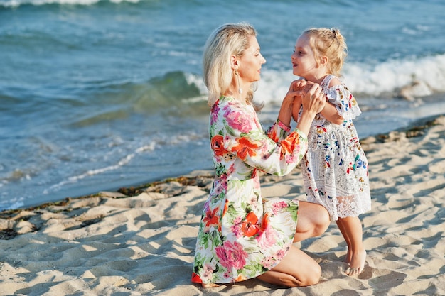 Bezpłatne zdjęcie matka i piękna córka bawią się na plaży portret szczęśliwej kobiety z uroczą małą dziewczynką na wakacjach