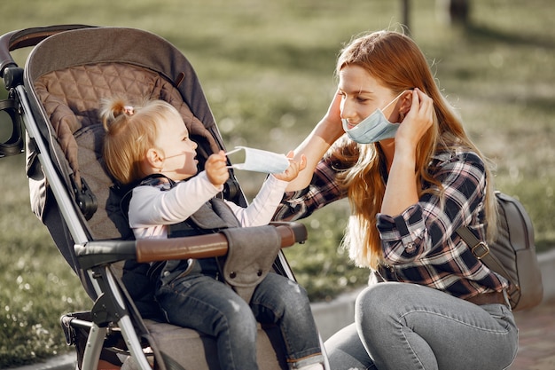 Matka Nosi Maskę Na Twarz. Mama Z Wózkiem Dziecięcym Podczas Pandemii Na Spacerze Na świeżym Powietrzu.