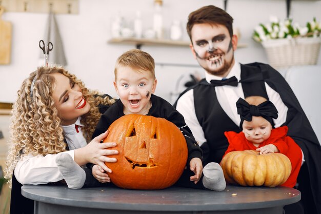 Matka, ojciec i dzieci w kostiumach i makijażu. Rodzina przygotowuje się do świętowania Halloween.