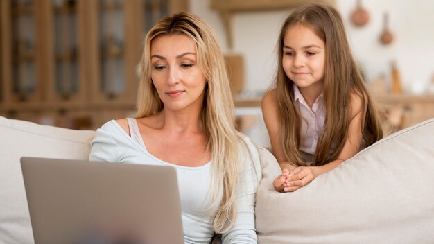 Matka pracuje na laptopie z domu z córką oglądając