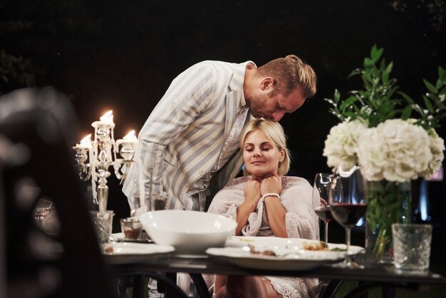Bezpłatne zdjęcie mąż całuje swoją żonę. piękna para dorosłych ma luksusowy obiad wieczorem