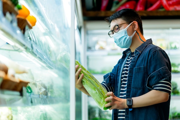 Mąż noszący maskę chroniącą twarz wybierz vegetable zakupy w supermarkecie spożywczym nowa koncepcja zdrowego stylu życia i pomysłów