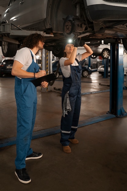 Mechanicy płci męskiej i żeńskiej pracujący w sklepie przy samochodzie
