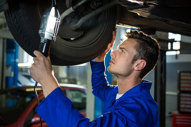 Mechanik badając opona samochodu za pomocą latarki