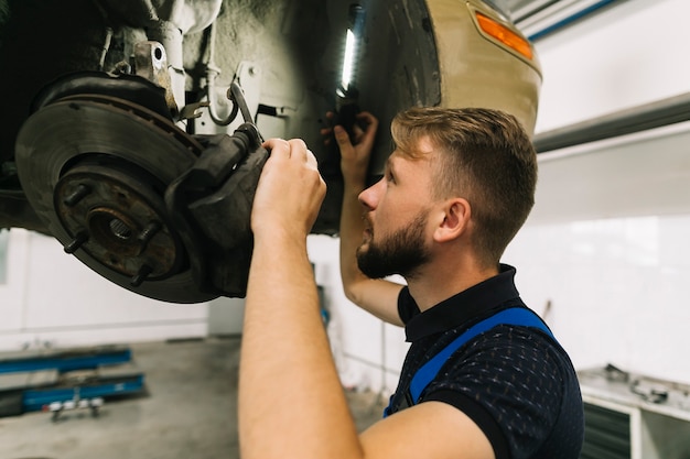 Bezpłatne zdjęcie mechanik kontrolujący układ kół