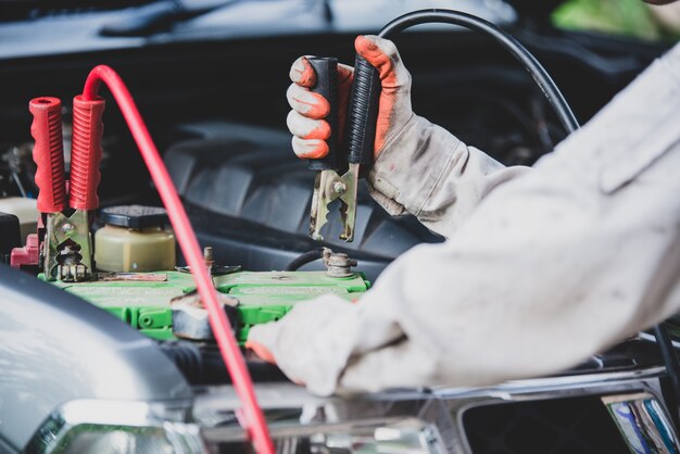 Mechanik samochodowy w białym mundurze stojącym i trzymający klucz, który jest niezbędnym narzędziem dla mechanika