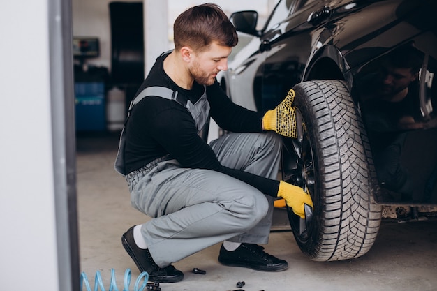 Bezpłatne zdjęcie mechanik samochodowy zmieniający koła w samochodzie