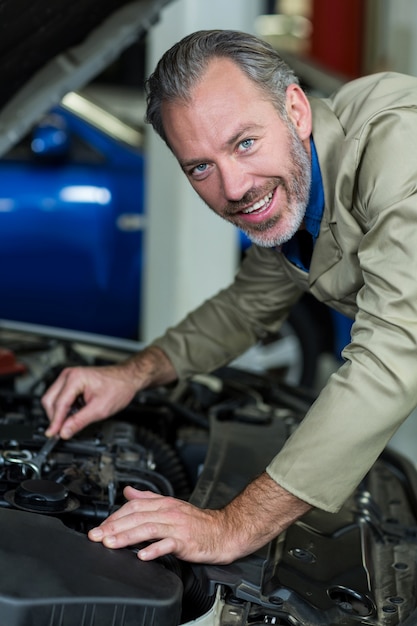 Bezpłatne zdjęcie mechanik uśmiecha się podczas serwisowania silnika samochodu