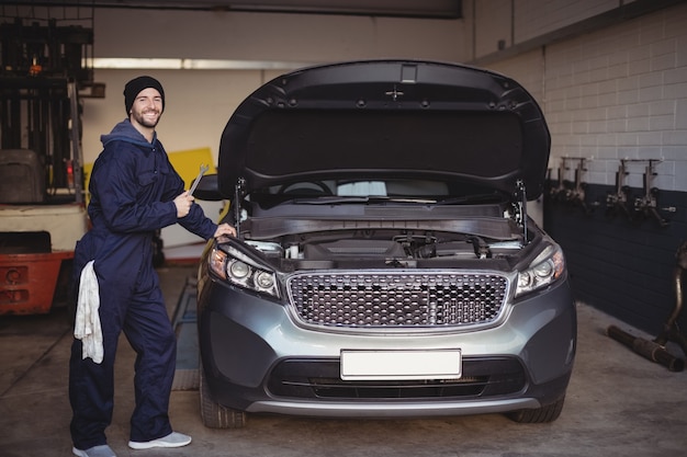 Mechanik, uśmiechając się i trzymając narzędzie klucza w garażu