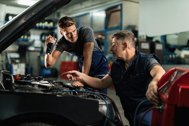 Bezpłatne zdjęcie mechanika samochodowa komunikująca się podczas wykonywania diagnostyki układu klimatyzacji w warsztacie