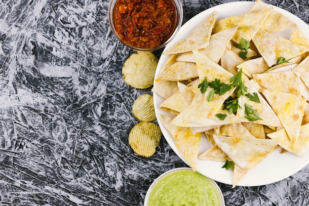 Bezpłatne zdjęcie meksykańscy nachos z pikantność na marmurowym tle
