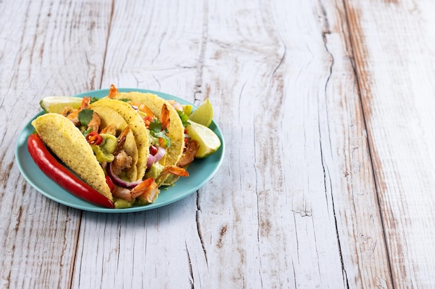 Meksykańskie tacos z krewetkami guacamole i warzywami na drewnianym stole