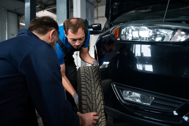 Męscy mechanicy pracujący razem nad samochodem w sklepie