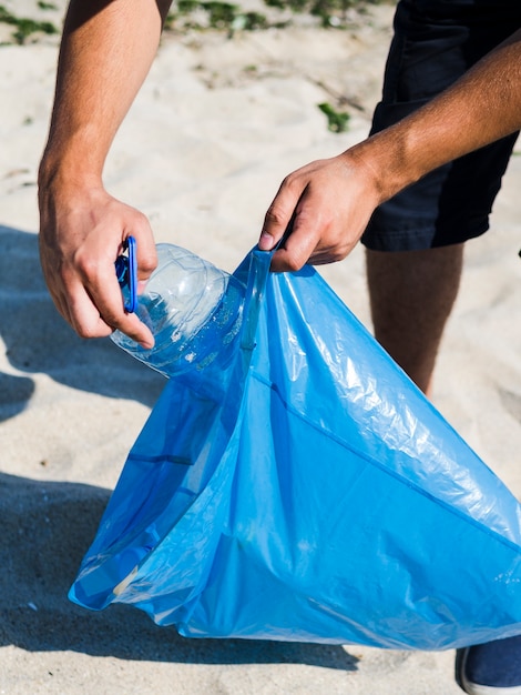 Męska Ręka Stawia Przejrzystą Plastikową Butelkę W Błękitnym Torba Na śmiecie