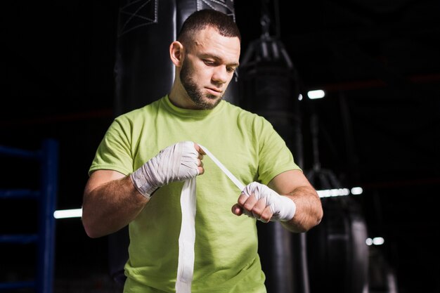 Męski bokser w koszulce zakładający ochronę dłoni