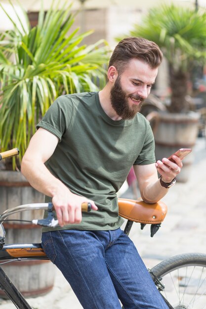 Męski cyklisty obsiadanie na rowerowym używa telefonie komórkowym