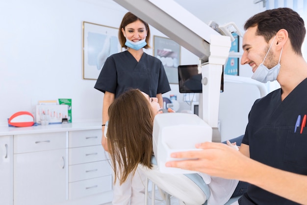 Męski dentysta skanuje żeńskiego pacjenta zęby z promieniowaniem rentgenowskim maszyną