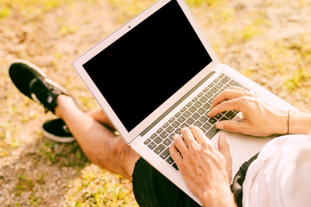 Męski freelancer używa laptop podczas gdy pracujący outside