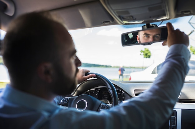 Bezpłatne zdjęcie męski kierowca przystosowywa samochodu tylnego widoku lustro
