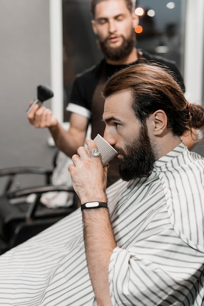 Męski klient pije filiżankę herbata w fryzjera męskiego sklepie