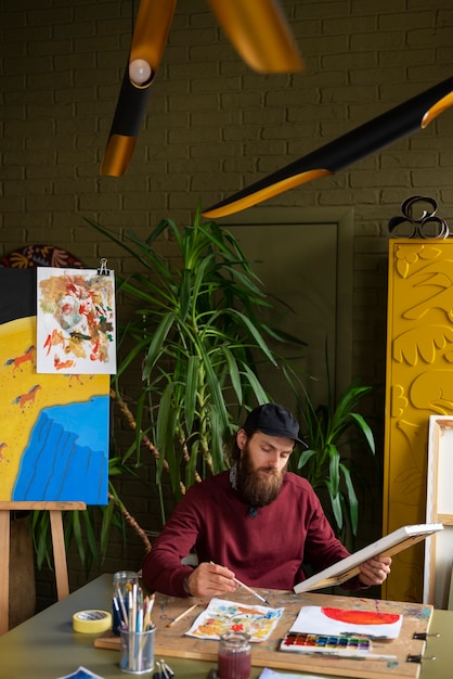 Bezpłatne zdjęcie męski malarz w studiu używający akwareli na swojej sztuce