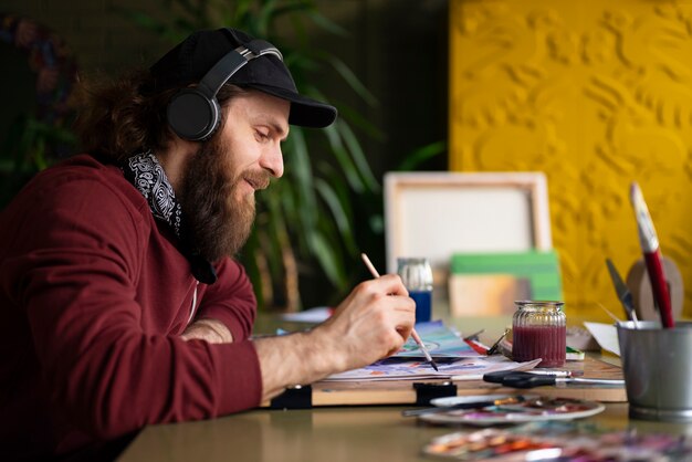 Męski malarz w studiu używający akwareli na swojej sztuce