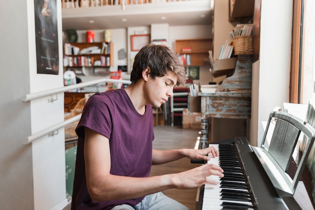 Męski nastolatek bawić się pianino