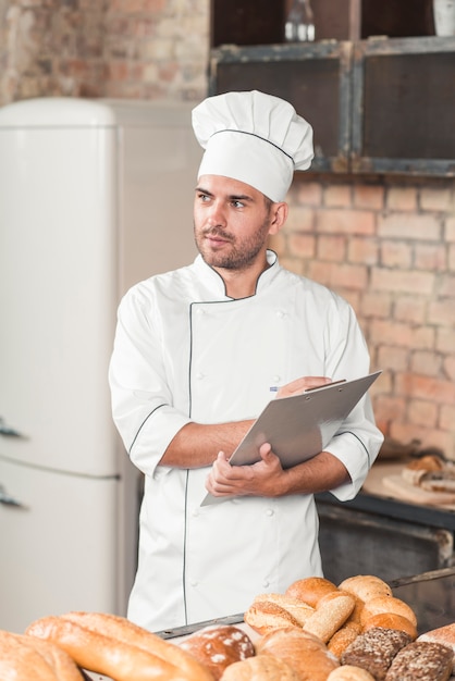 Bezpłatne zdjęcie męski piekarniany writing na schowku z piec chlebami na kuchennym worktop