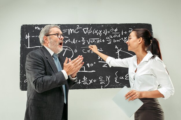 Męski profesor i młoda kobieta przeciw chalkboard w sala lekcyjnej