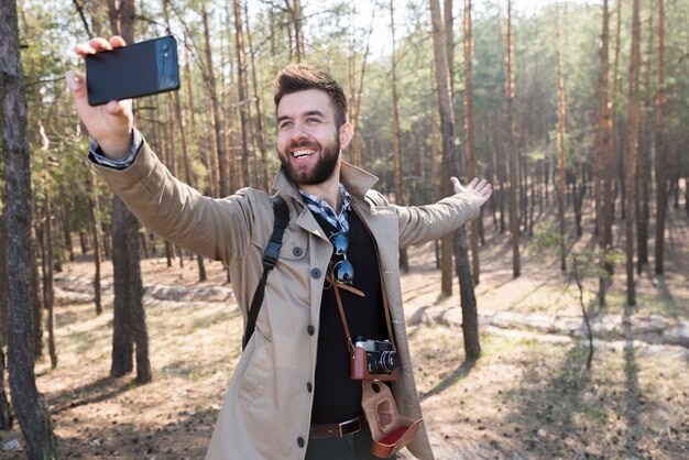 Męski wycieczkowicz bierze selfie na telefonie komórkowym w lesie