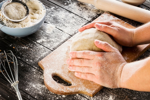 Bezpłatne zdjęcie męskie ręce wyrabiania ciasta na posypane mąką tabeli