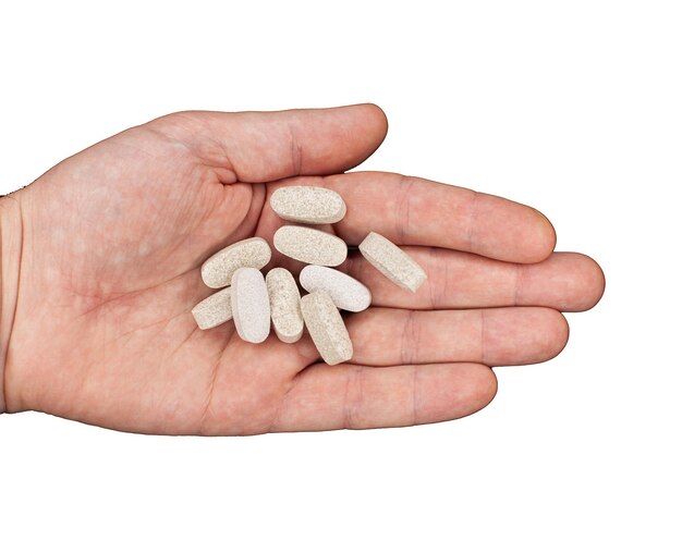 Męskiej ręki trzymającej pigułki. kapsułki są białe. leki. wyizoluj na białym tle. lekarstwo na choroby. koncepcja uzależnienia od narkotyków. leczenie choroby za pomocą leków.