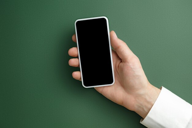 Męskiej ręki trzymającej smartfon z pustym ekranem na zielono