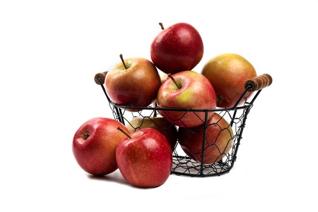 Metalowy kosz świeżych dojrzałych jabłek na białym tle.