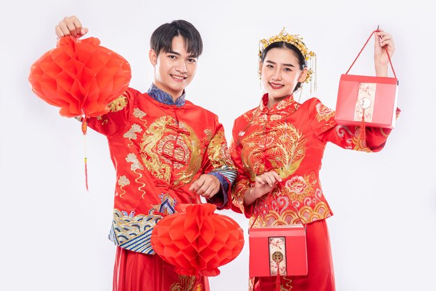 Mężczyzn i kobiet noszących cheongsam Stojący trzymając czerwoną torbę i latarnię o strukturze plastra miodu