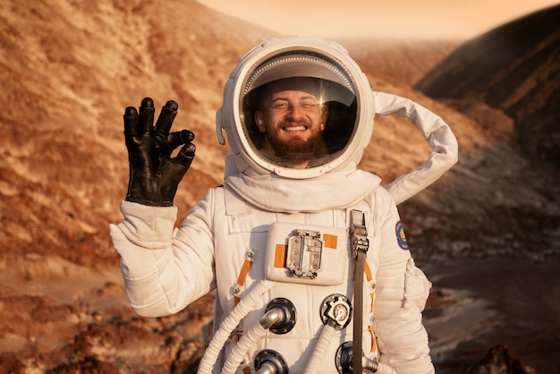 Bezpłatne zdjęcie mężczyzna astronauta dający znak porządku podczas misji kosmicznej na innej planecie
