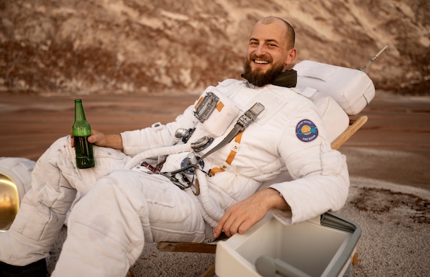 Mężczyzna astronauta pijący piwo podczas misji kosmicznej na nieznanej planecie