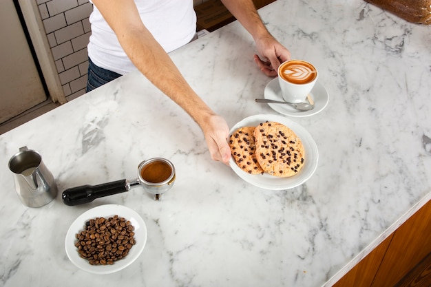 Bezpłatne zdjęcie mężczyzna barista z ciasteczkami i cappuccino