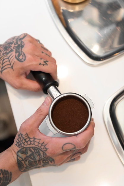 Bezpłatne zdjęcie mężczyzna barista z tatuażami przygotowujący kawę do ekspresu do kawy