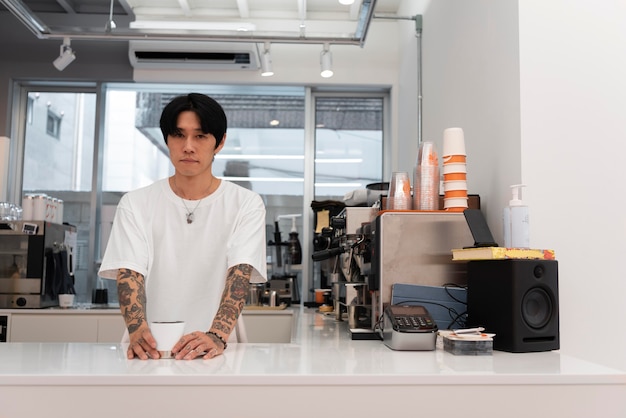 Mężczyzna barista z tatuażami serwujący kawę przy ladzie